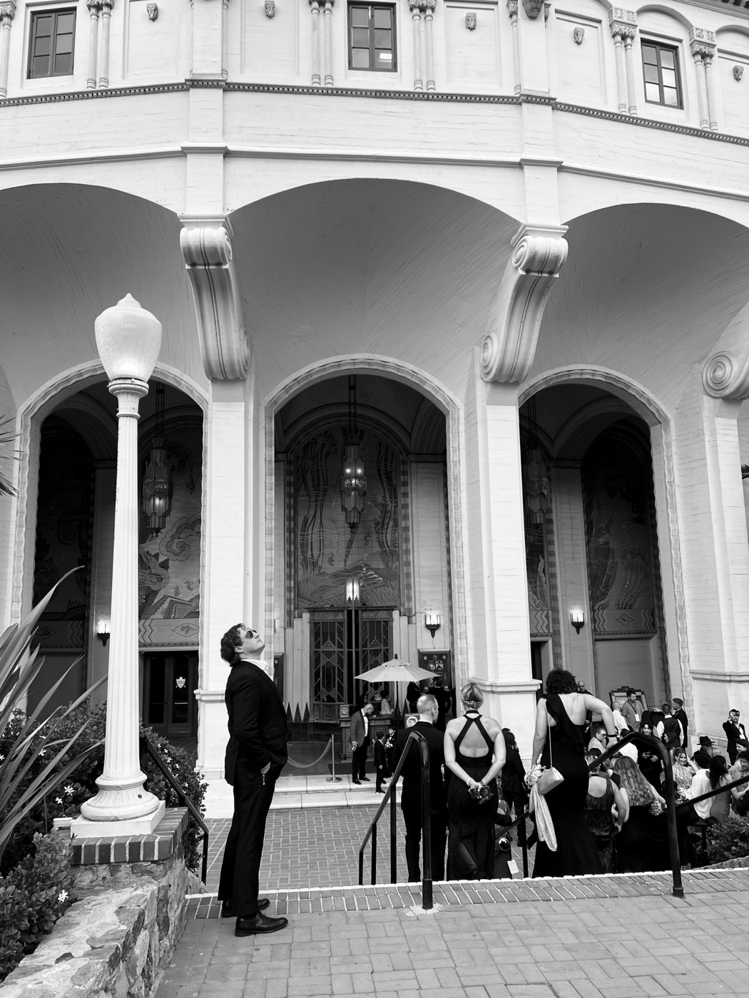 Jason Pelsey in a dark suit looking up at the arched entrance of the Avalon Theater on Catalina Island, black and white
