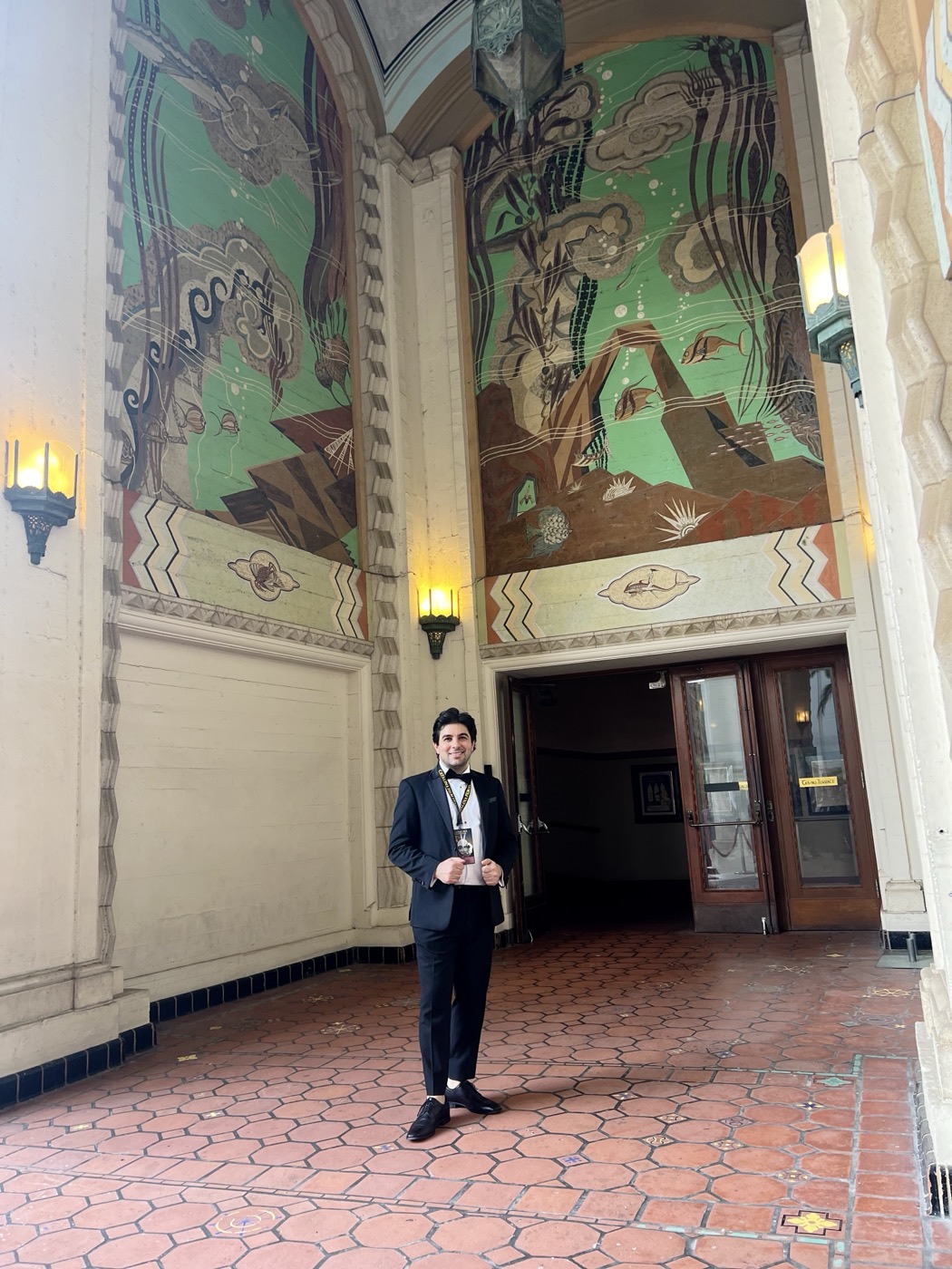 Remi Gangarossa in a tuxedo beneath the painted murals of the Avalon Theater entrance