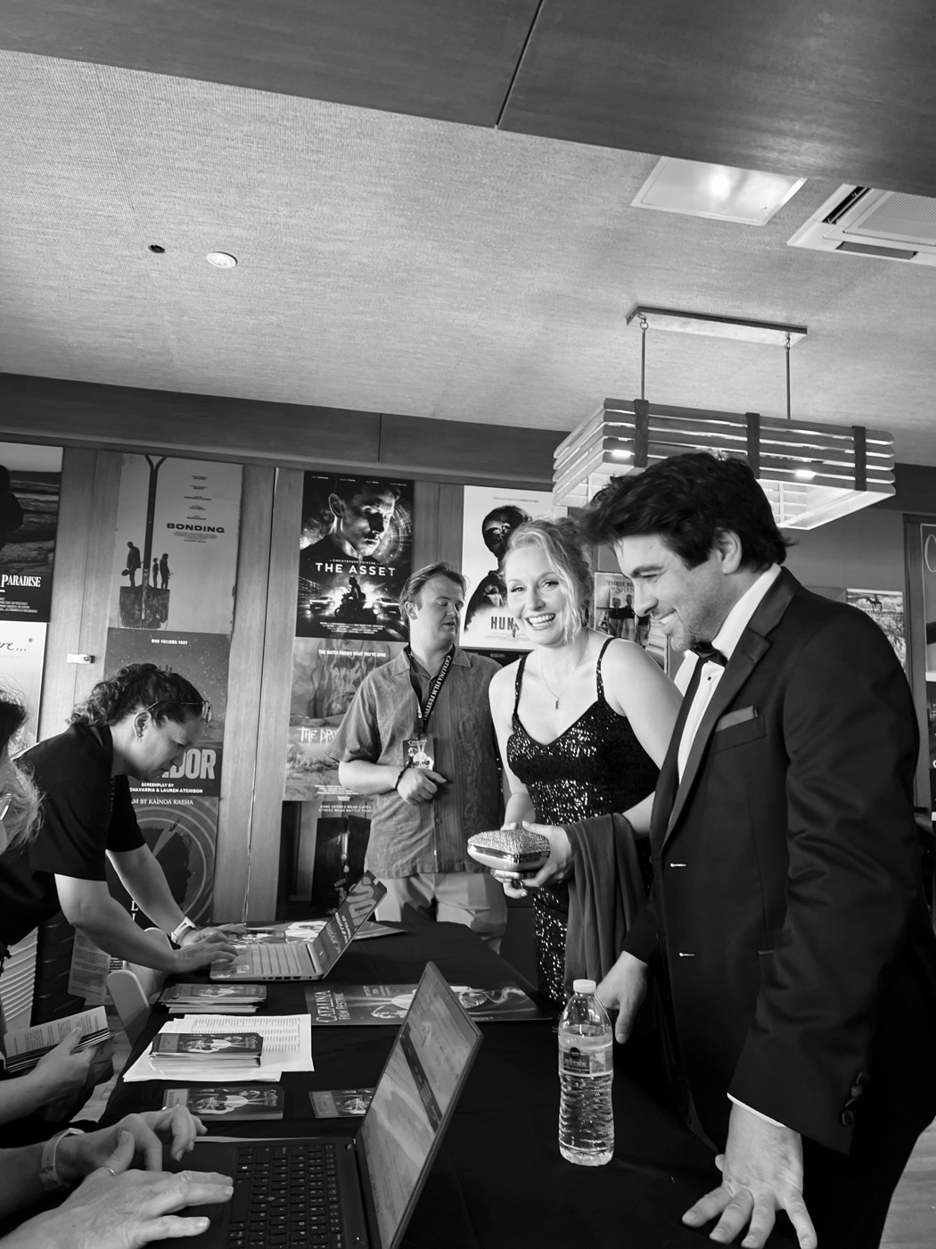 Remi Gangarossa in a tuxedo checking in at the festival desk, black and white