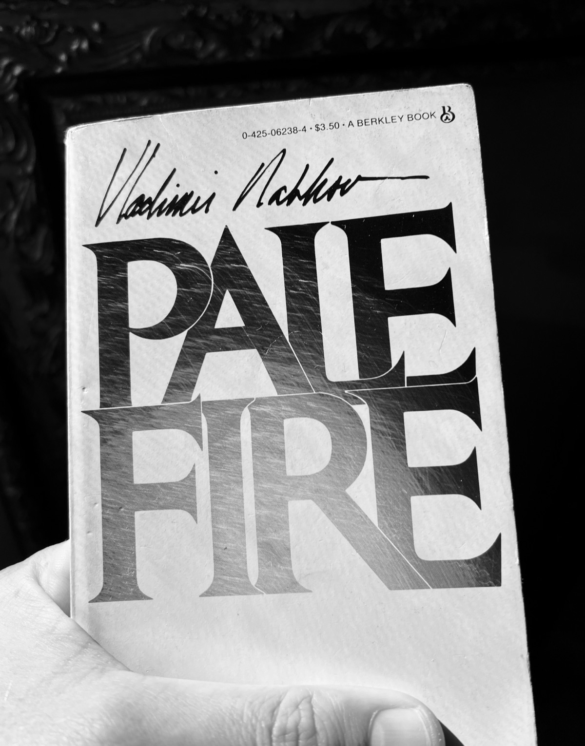 Rob Watt's hand holding a worn Berkley paperback of Pale Fire by Vladimir Nabokov, black and white