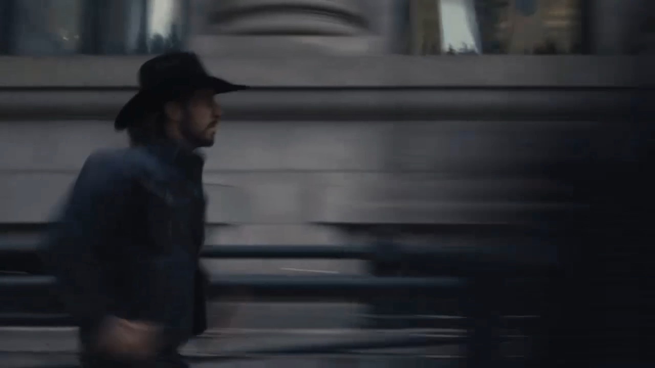 Man in a cowboy hat striding through downtown Dallas in a motion blur, from the Boot Barn Dallas commercial